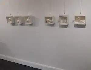 Wall-mounted series of delicate white box sculptures with paper and mixed media elements by Penelope Steel. Each piece explores themes of form, space, and movement in miniature scenes.
